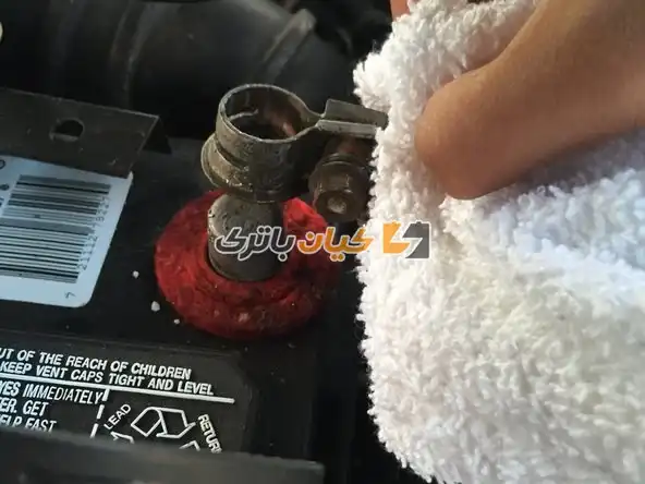 آموزش تعویض بست باتری ماشین 13 با استفاده از یک پارچه، ترمینال مثبت را با دقت از گره باتری جدا کنید.